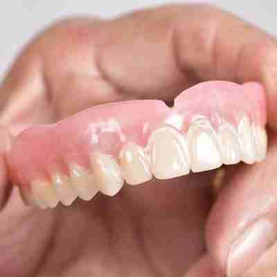 a human hand holding full dentures