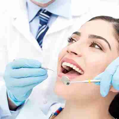 Oral Examination Dr. Michael Koumas performing an oral examination on a young woman with brown eyes and a white smile